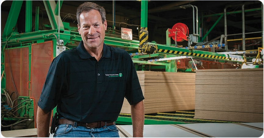 Timber Products employee sitting in front of stacks of lumber.