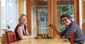 Man and woman playing chess in their home.