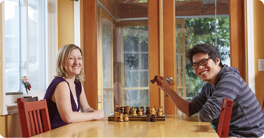 Man and woman playing chess in their home.