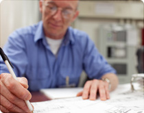 Close-up of a man writing on some paper at a table.