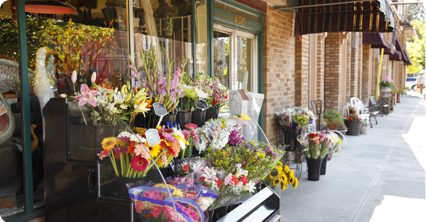 Retail street scene with beautiful flowers for sale in front of a small business.
