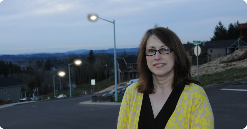 a woman with glasses standing in front on new led streetlights