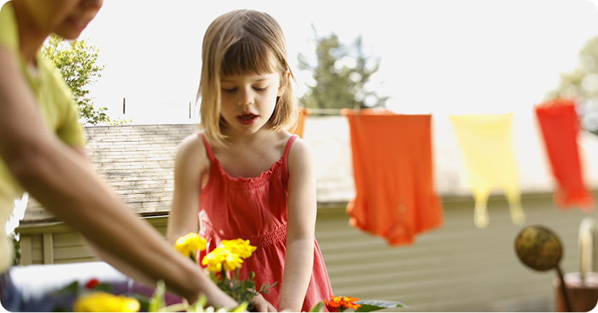 little girl planting flowers with her mother