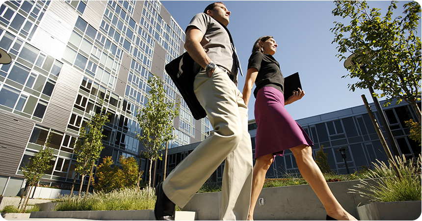 a business woman and man walk in front of an office building