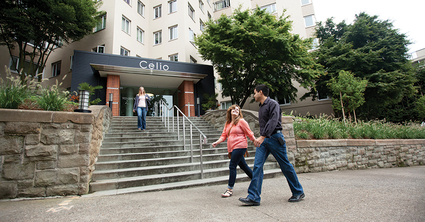 man and woman walking in front of a large apartment building