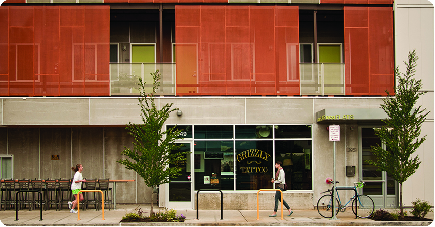 woman jogging by an urban storefront below an apartment building