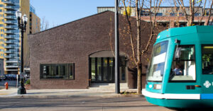 a tourqoise streetcar zooming by a brick building