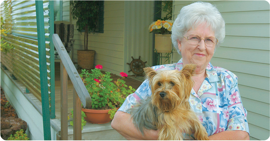 an elderly woman and her dog in front of her home