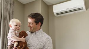 father and smiling son in front of a ductless heatpump