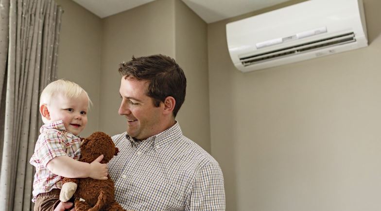father and smiling son in front of a ductless heatpump