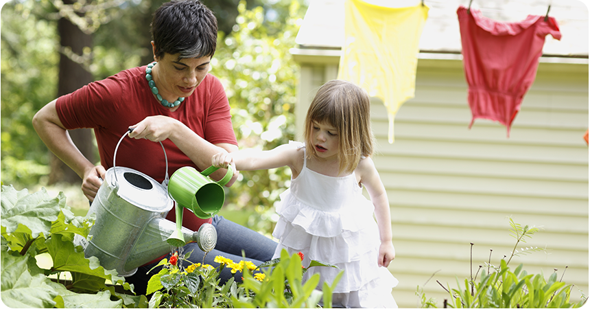 Mother and daughter watering garden plants