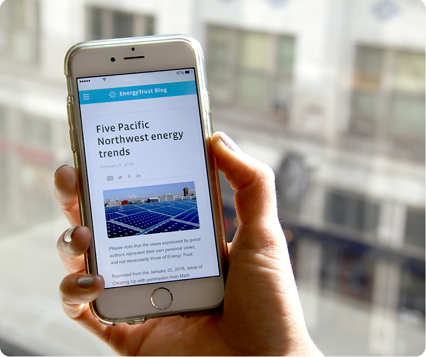 a closeup of a hand holding a smartphone with the energy trust blog on the screen