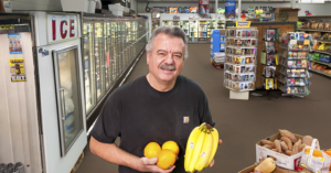 man holding oranges and bananas in grocery store