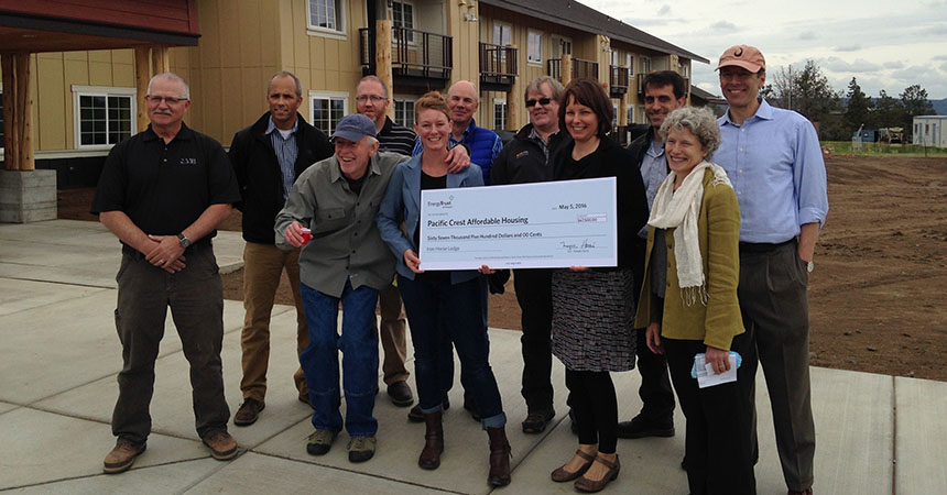 a group of recipients holding a big check in front of the completed Iron Horse Lodge