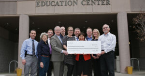 a group of people holding a big check in front of the Education Center at Oregon Community College