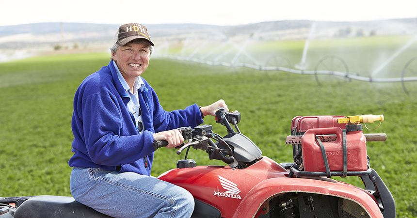 a woman on a bright red 4-wheeler, in a green farm field