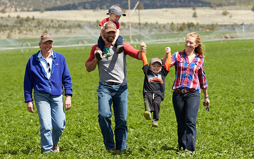 a family walking across a farm field with a dog and two children