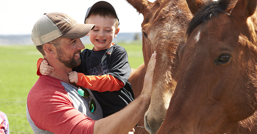 farmer and young boy petting a brown horse