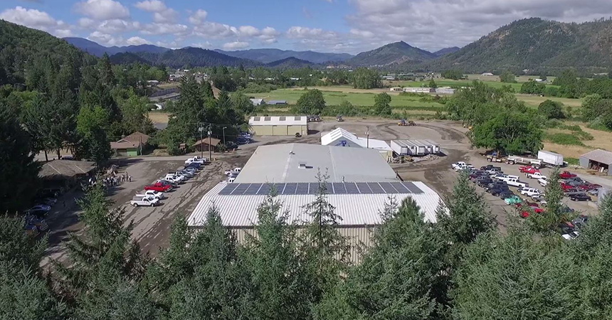 aerial view of a solar instalation on a warehouse building surrounded by trees