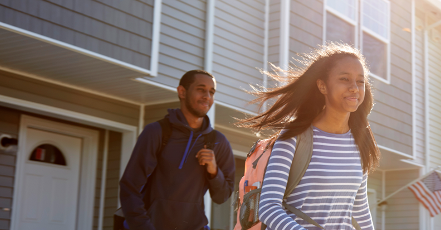 a boy and girl walking out of their home to school