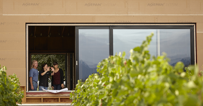 a woman gesturing with her hands to a couple at the Cowhorn Vineyard