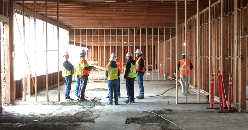 a construction team with hardhats in a wood frame building in progress