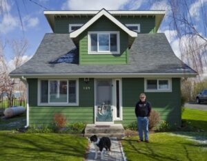 man and dog in front of a green house