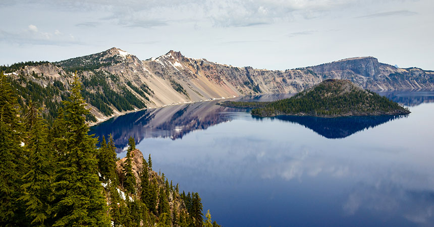 a picture of Crater Lake, a bright blue lake surrounded by mountains with a small island in the middle