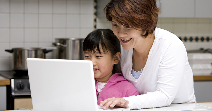 a mother and daughter smiling working on a laptop computer