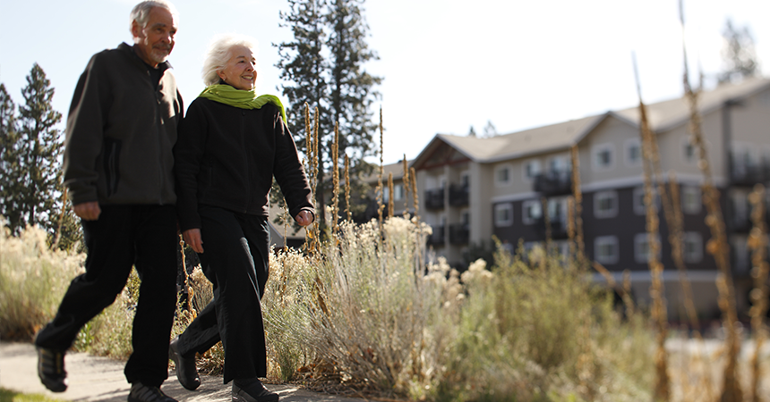 an older couple walking in front of a multifamily building