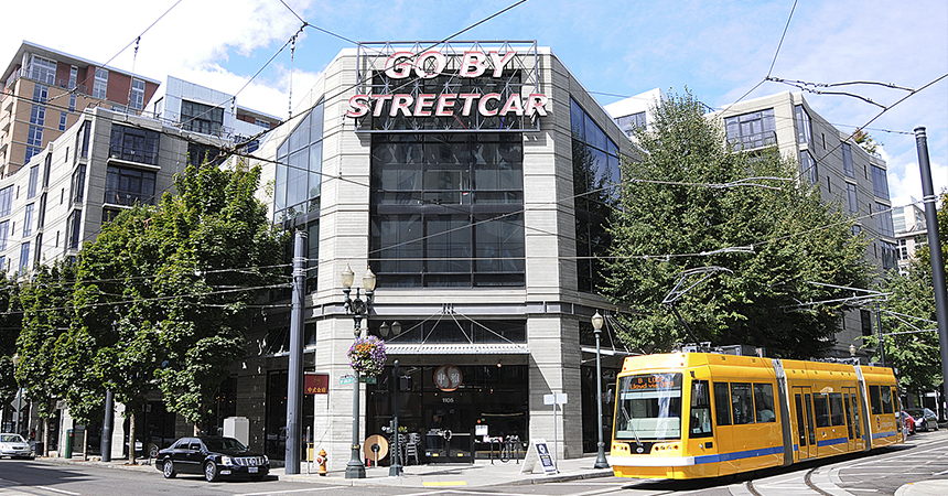 a neon sign saying "go by streetcar" with a yellow street car passing by