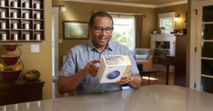 man reading the back of a smart thermostat box in his home