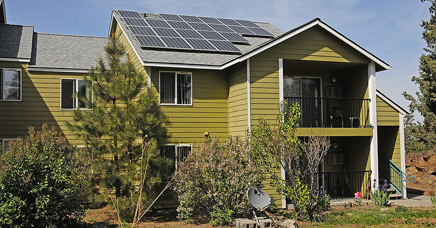 Green apartment building with solar panels on roof