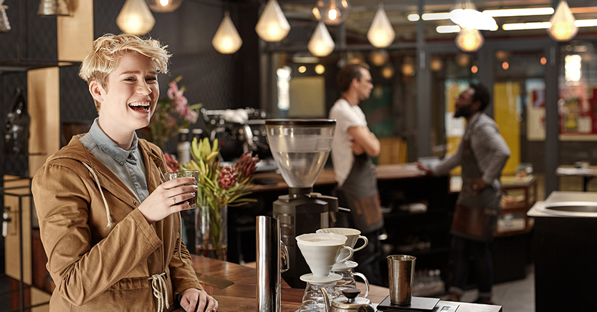 woman drinking a cup of coffee in a brightly lit coffee shop