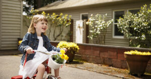 little girl riding a red bike on a sunny day