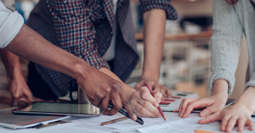 a closeup of multiple people working on blueprints