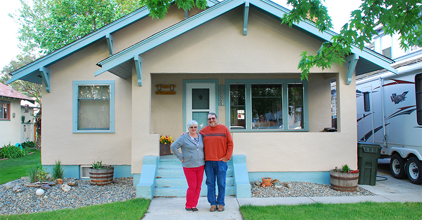 A couple standing in front of their home.