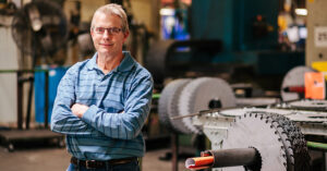 a man in a blue polo shirt standing in front of table saws