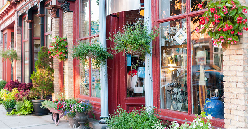 A view of the exterior of a building with small shops decorated with hanging flower baskets.