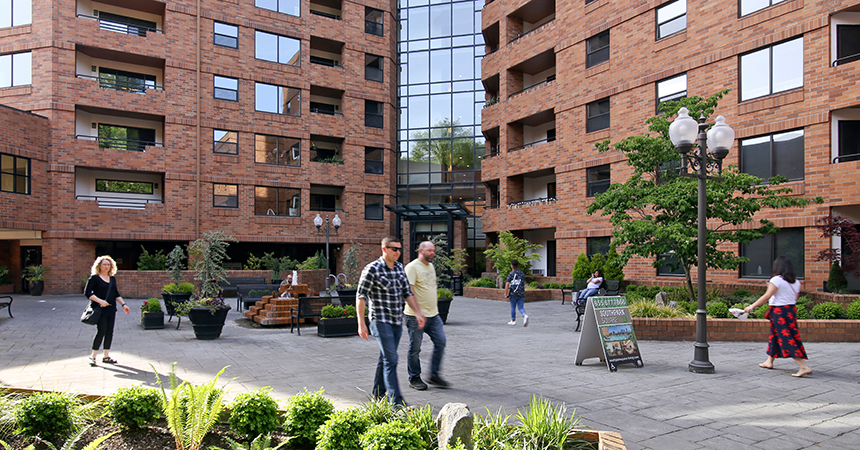 people walking around in front of a new brick apartment building