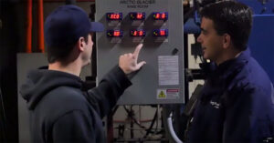 two men working on a electrical box in a cold storage facility