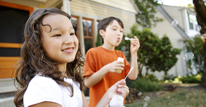 two children outside a house blowing bubbles