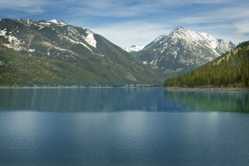 a picture of snow capped mountains behind a lake, the wallowas