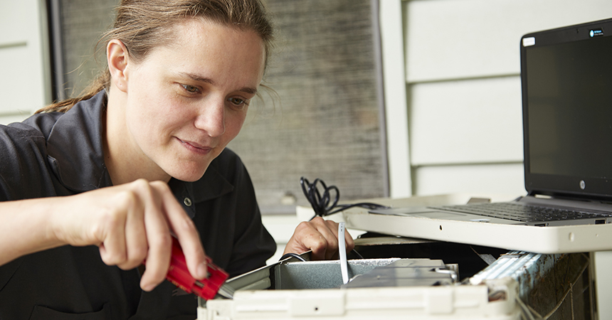 a woman using a screwdriver on some equipment