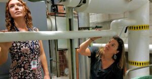 Commercial SEM intern Cacey Thomas and sustainability coordinator Jackie Wilson observing the equipment in the boiler room at Bear Creek Elementary School in Bend.