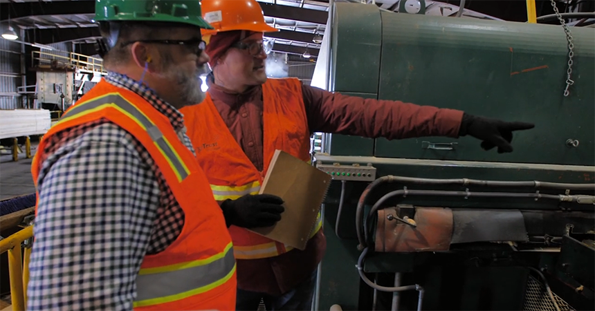 two men in hard hats at a lumber mill