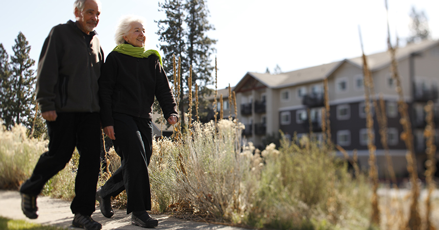 two seniors walking on a crisp fall day in front of a retirement center