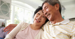 Senior Asian Couple At Home Relaxing On Sofa Together