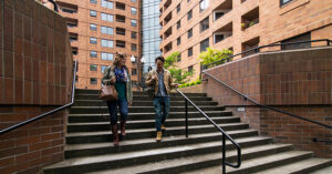 a man and a woman walking in front of a nice multifamily building