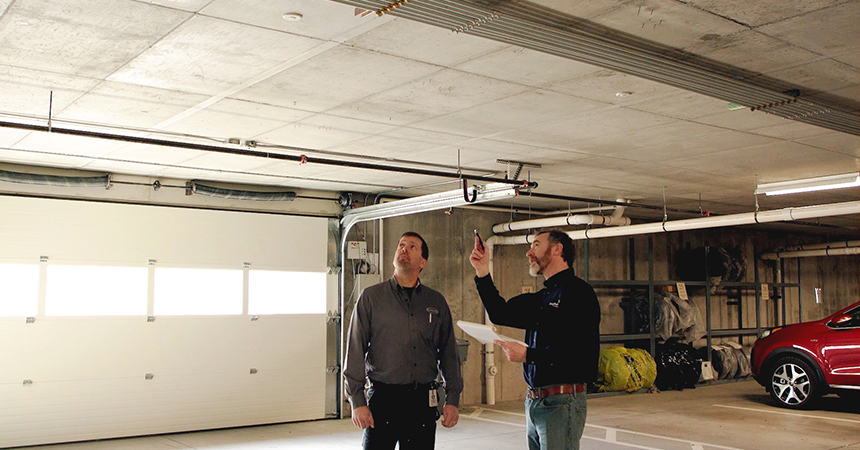 a technician and a property manager in a parking garage inspecting the lighting